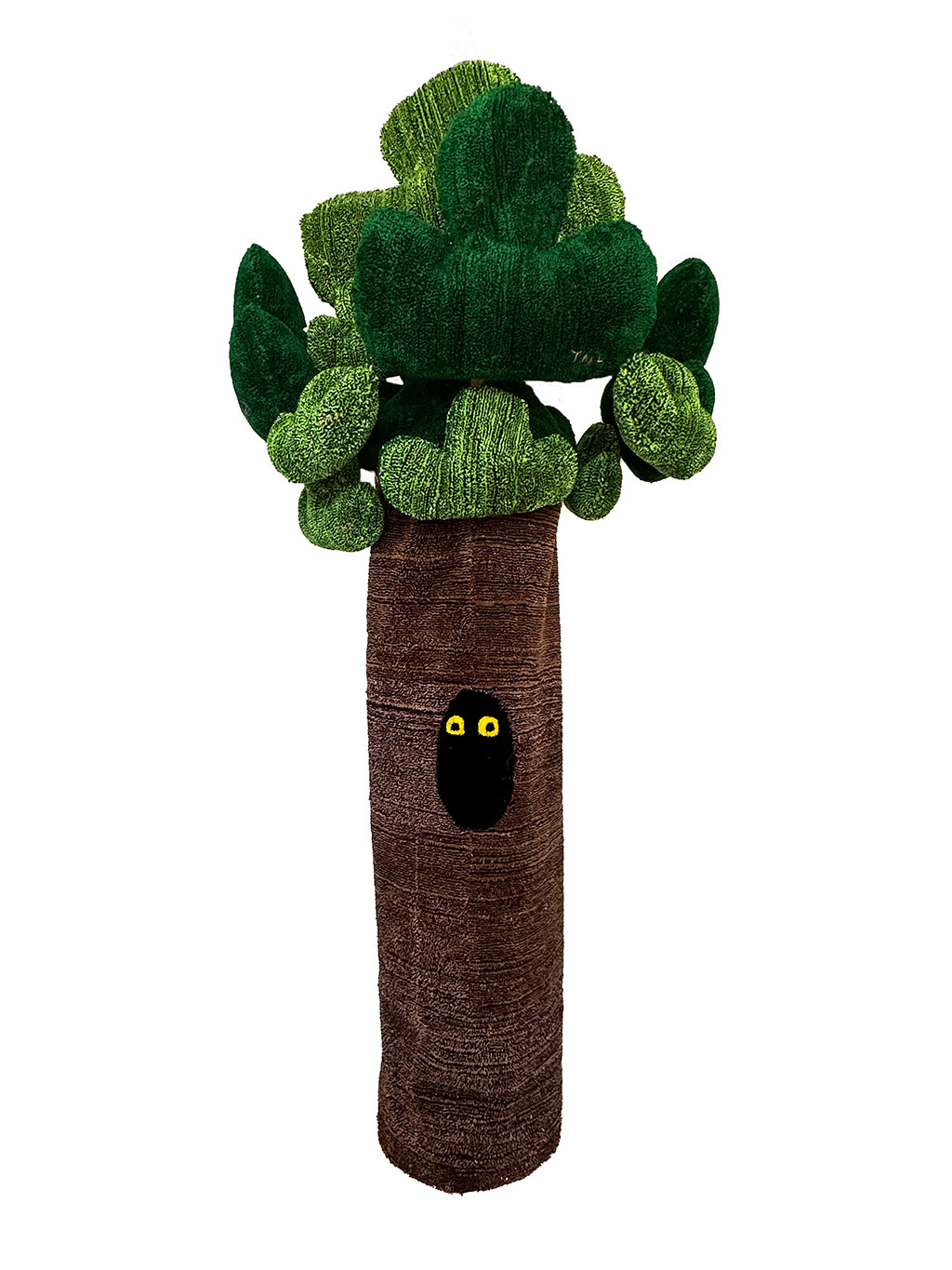 Soft sculpture of a tree with a two yellow eyes coming out of a hole in the trunk.