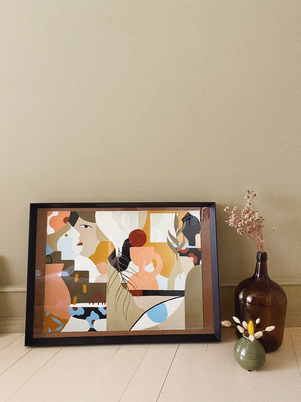 Framed Madi abstract art print on a wall next to decorative vases.