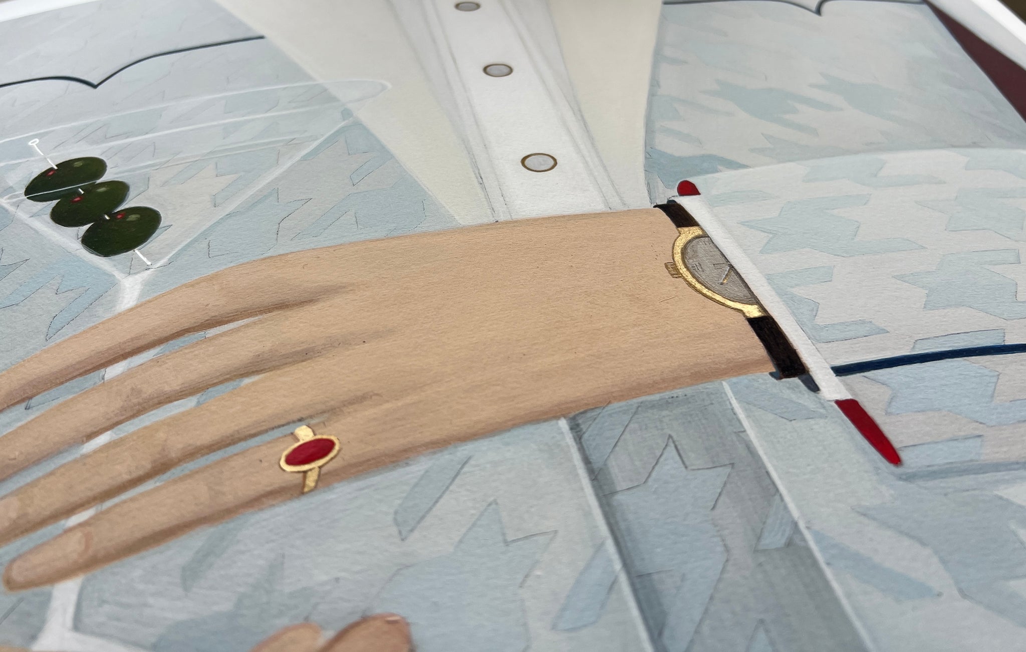 Hand wearing a gold ring with a red stone on a textured surface