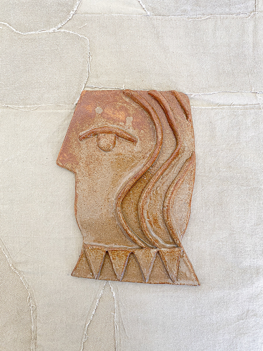 brown side profile of a face made from ceramic clay