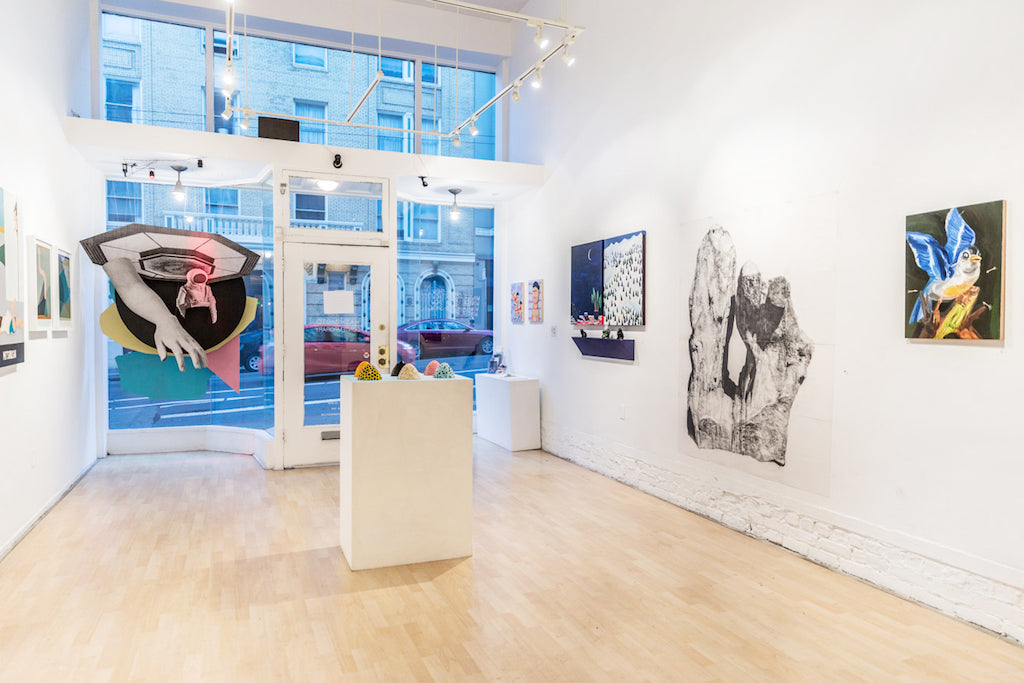 Emma Websters contemporary art gallery showcases various artworks on white walls, featuring Fear of Flying, an oil on panel abstract painting, and black-and-white photos. A 2017 sculpture sits on a pedestal. Large front windows provide street views while bright track lighting illuminates the space.